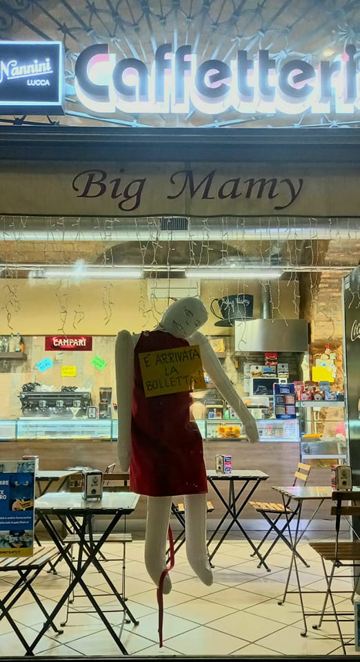 Caro bollette, nella vetrina di un bar un manichino impiccato con un cartello al collo: “È arrivata la bolletta!”